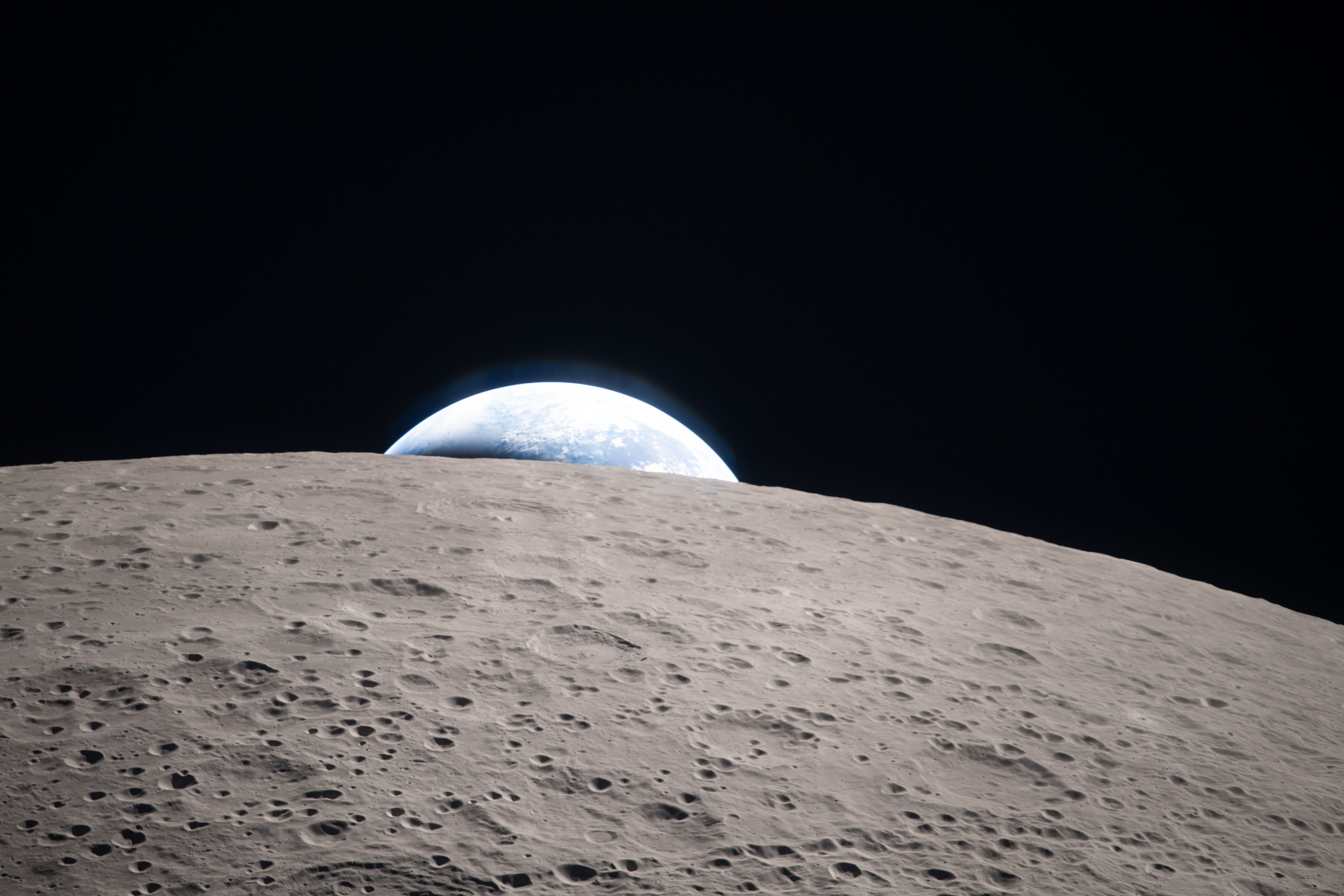 The Earth barely visible behind the Moon's limb