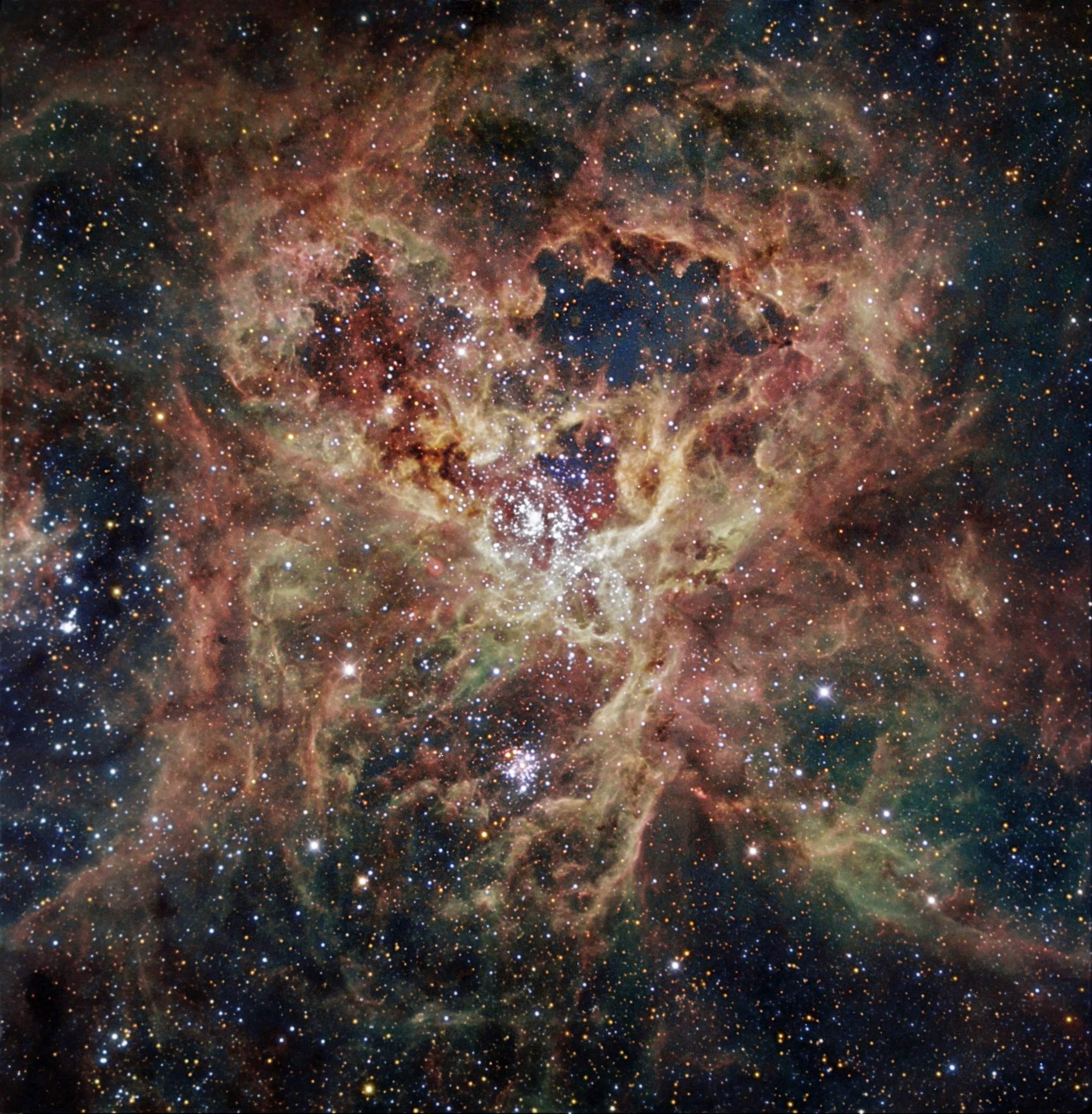 An image showing a birghty very wispy nebula with sever star clusters including a massive one in the middle